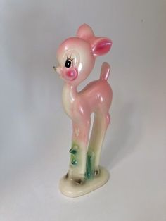 a small pink and white deer figurine on a white surface with one eye open