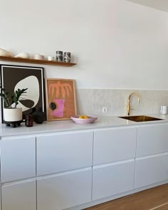 a kitchen with white cabinets and gold faucets on the counter top, next to a potted plant