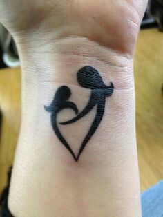 a small tattoo on the wrist of a woman holding a baby in her arms,