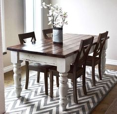 a dining room table and chairs in front of a window with an area rug on the floor