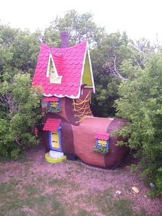 a house made out of a mushroom like structure in the middle of some bushes and trees