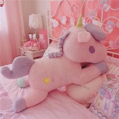 a large pink stuffed unicorn laying on top of a bed