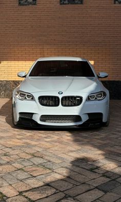 a white car is parked in front of a brick wall and some bricks on the ground