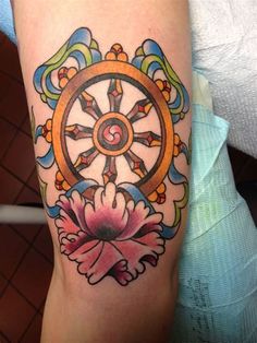 a woman's arm with a wheel and flower tattoo design on the left forearm