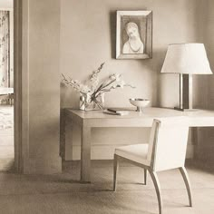 an old photo of a desk and chair in a room with a painting on the wall