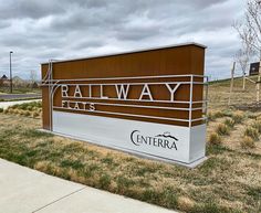 a sign for the entrance to railway flats in front of a grassy area with trees and bushes