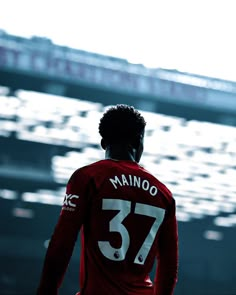 a man standing in front of a stadium with his back to the camera, wearing a red jersey