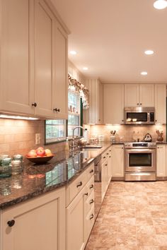 a large kitchen with white cabinets and granite counter tops on the counters is lit by recessed lights