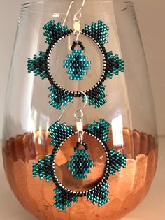 a pair of beaded hoop earrings sitting on top of a vase