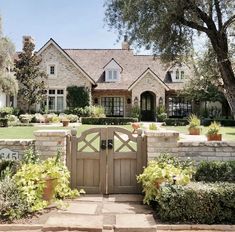 a large house with a gate in front of it and lots of plants around the entrance