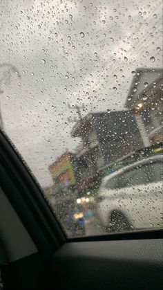 rain drops on the windshield of a car as it drives down a street in front of houses