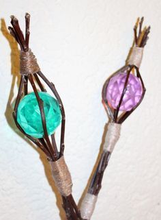 two branches with flowers made out of wire and colored glass beads are shown in front of a white wall