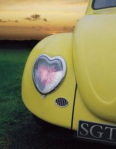 the front end of a yellow vw bug with a heart on it's bumper