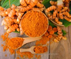 tumerical and ginger powder in wooden spoons next to green leafy leaves