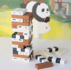 a stack of lego blocks sitting on top of a table next to a panda bear