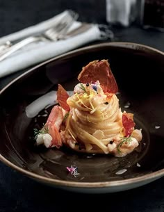 a black plate topped with pasta and shrimp