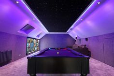 a pool table in the middle of a room with purple lighting on either side of it