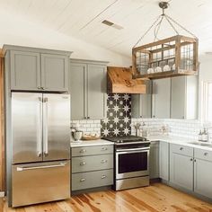 a kitchen with gray cabinets and stainless steel appliances in the center, along with wooden flooring