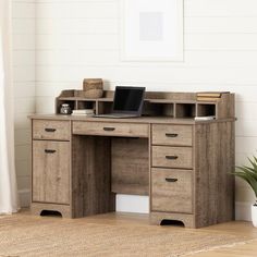 a wooden desk with drawers and a laptop computer on it in front of a white wall