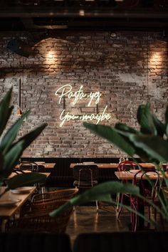 the interior of a restaurant with brick walls and neon signs on the wall above tables