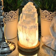 a white statue sitting on top of a table next to potted plants and candles