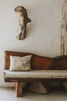 a wooden bench sitting next to a wall with a piece of driftwood on it