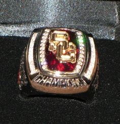 a close up of a ring on a black surface with white and red stones in the center