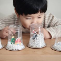 a young child playing with snow globes on a table