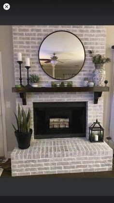 a living room with a fireplace, mirror and potted plants