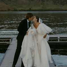 a bride and groom kissing on a dock