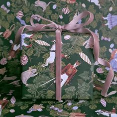 two presents wrapped in green wrapping paper with pink ribbon on them, sitting next to each other