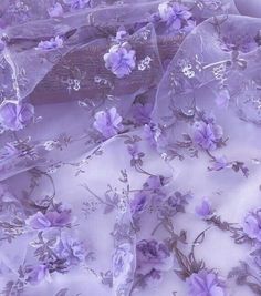 purple flowers and leaves on white fabric with sheer netting overlaying the image is very close up