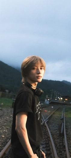 a young man standing on train tracks at dusk