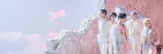 four people standing in front of a pink wall with snow on the ground and clouds behind them