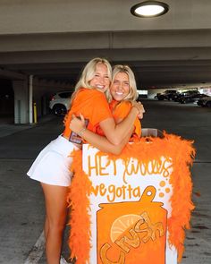 two women hugging each other in front of a sign