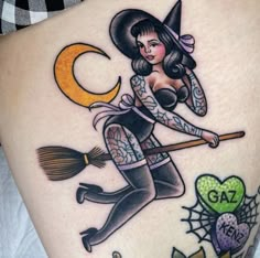 a woman with a witch hat and broom on her thigh