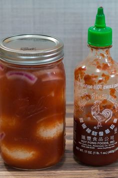 there are two jars with hot sauces in them on the table next to each other