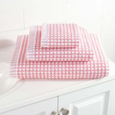 two pink and white towels sitting on top of a bathroom counter next to a sink