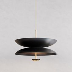 a black and gold pendant light hanging from a ceiling fixture with two circular lights above it