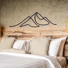 a bed with white linens and pillows in a rustic style bedroom, along with a wooden headboard