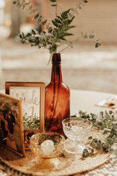 there is a vase with flowers in it and two pictures on the table next to it