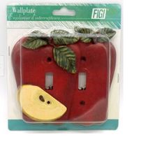 a red apple shaped light switch cover with green leaves on it's top and bottom