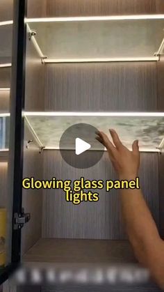 a hand is pointing at the glass panel lights on a shelf in a room with shelves