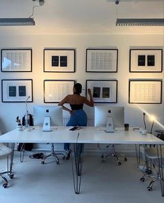 a woman standing in front of a white desk with multiple computers on top of it