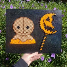 a person holding up a cross stitch picture with a jack - o - lantern on it