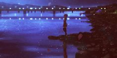 a person standing in the water at night with a bridge in the background and lights reflecting on the water