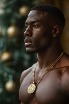 a man wearing a gold necklace with a medallion on it's neck and a christmas tree in the background