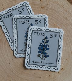 three stamps with blue flowers on them sitting on top of a piece of wood that has been cut into smaller pieces