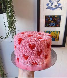 a cake with pink frosting and hearts on it sitting on top of a table