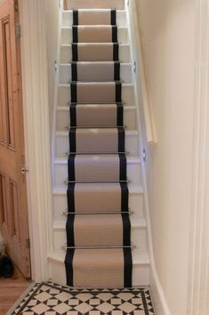 an image of a staircase with carpet on the bottom and black and white striped runner